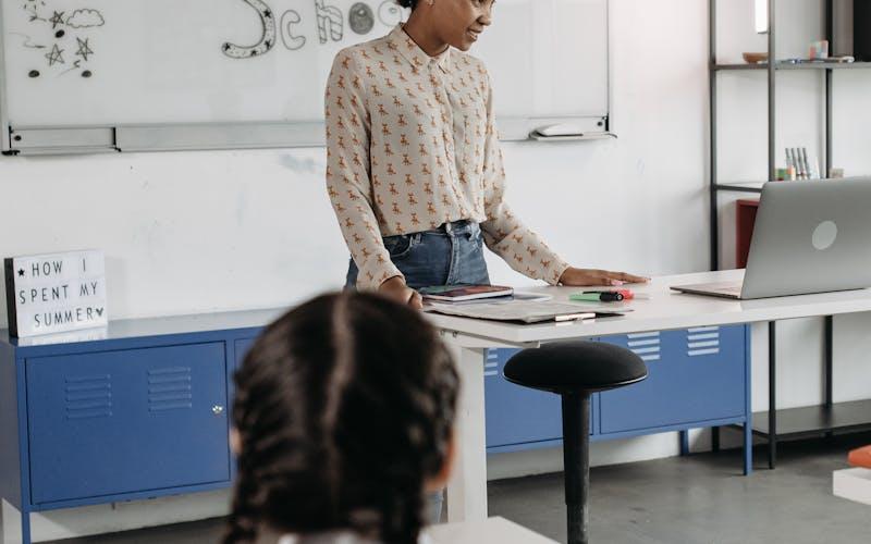 Enseignante devant son bureau préparant la rentrée dans une salle de classe