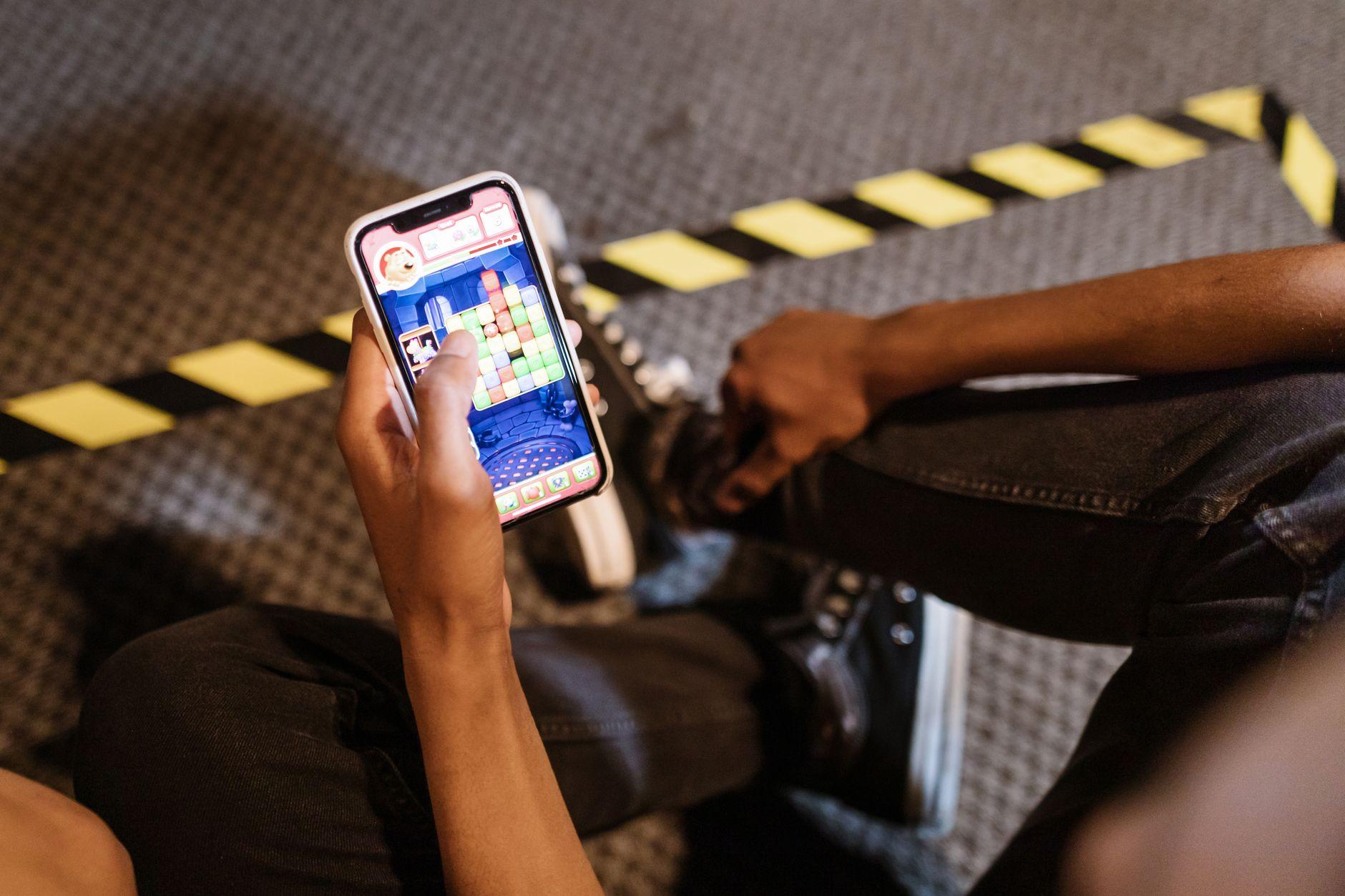 Personne jouant à un jeu coloré sur smartphone, illustrant la gamification mobile