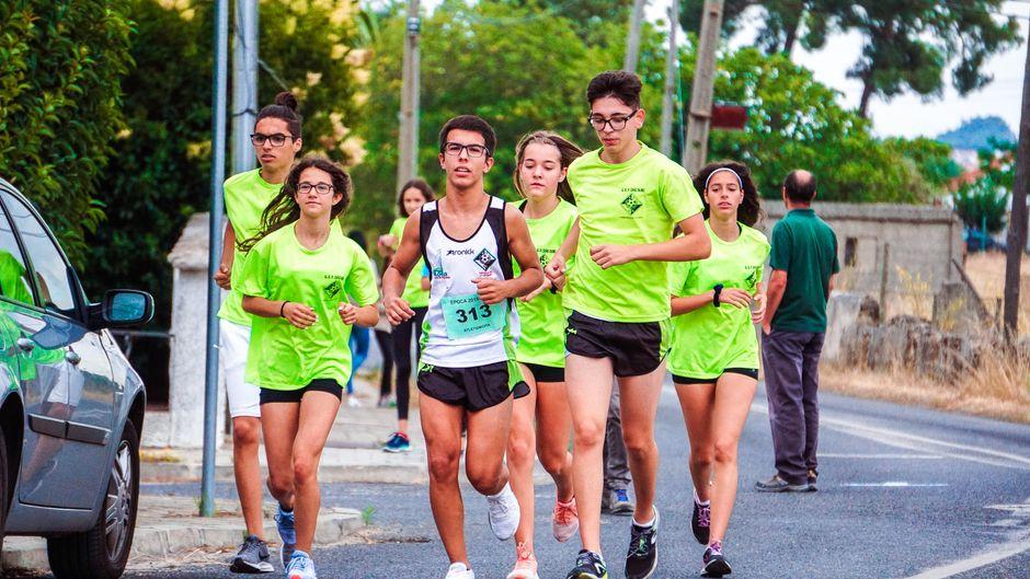 A group of young joggers running together on a road in bright green shirts, showcasing team effort.