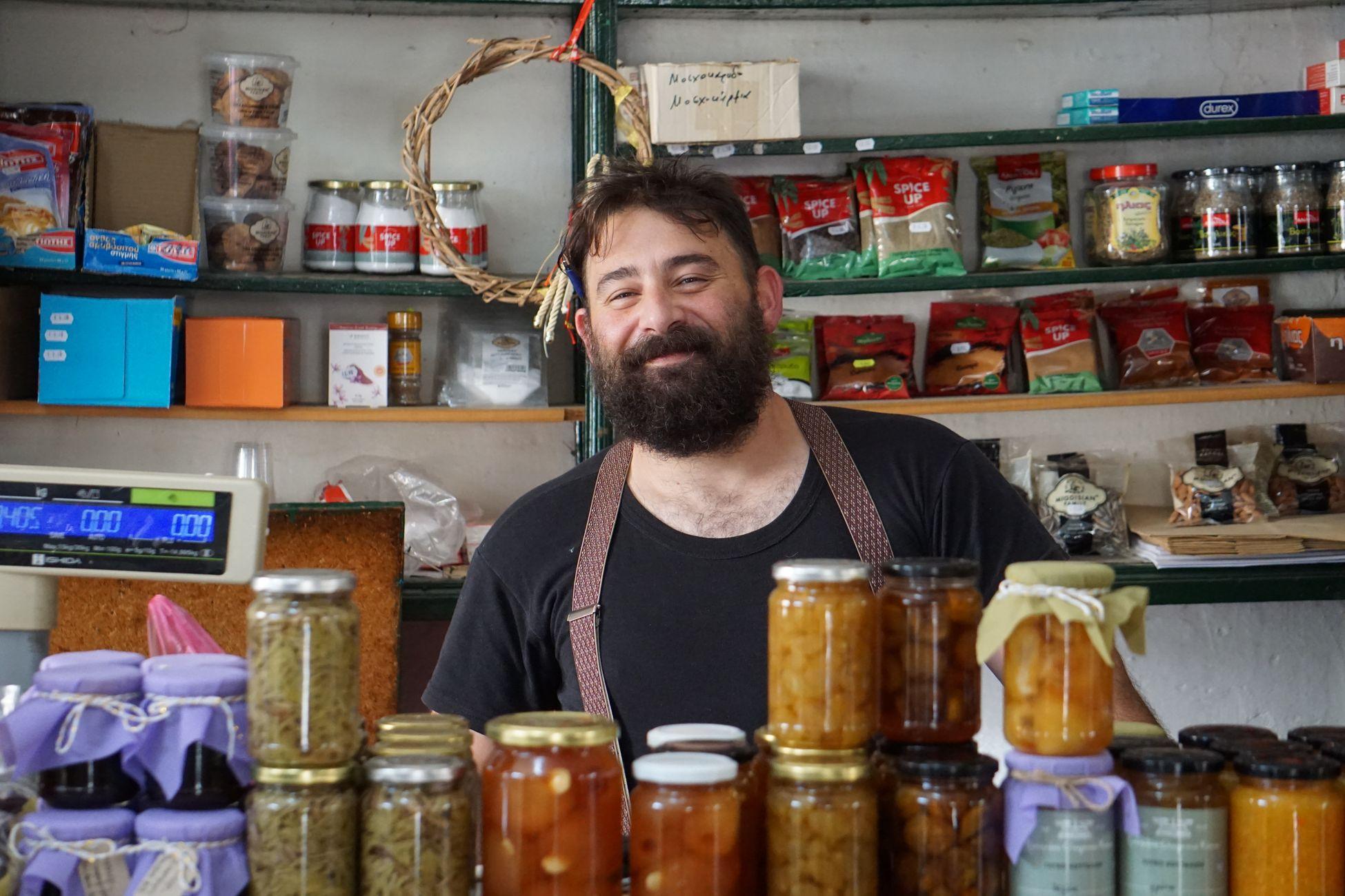 Commerçante souriante derrière des étagères de conserves artisanales