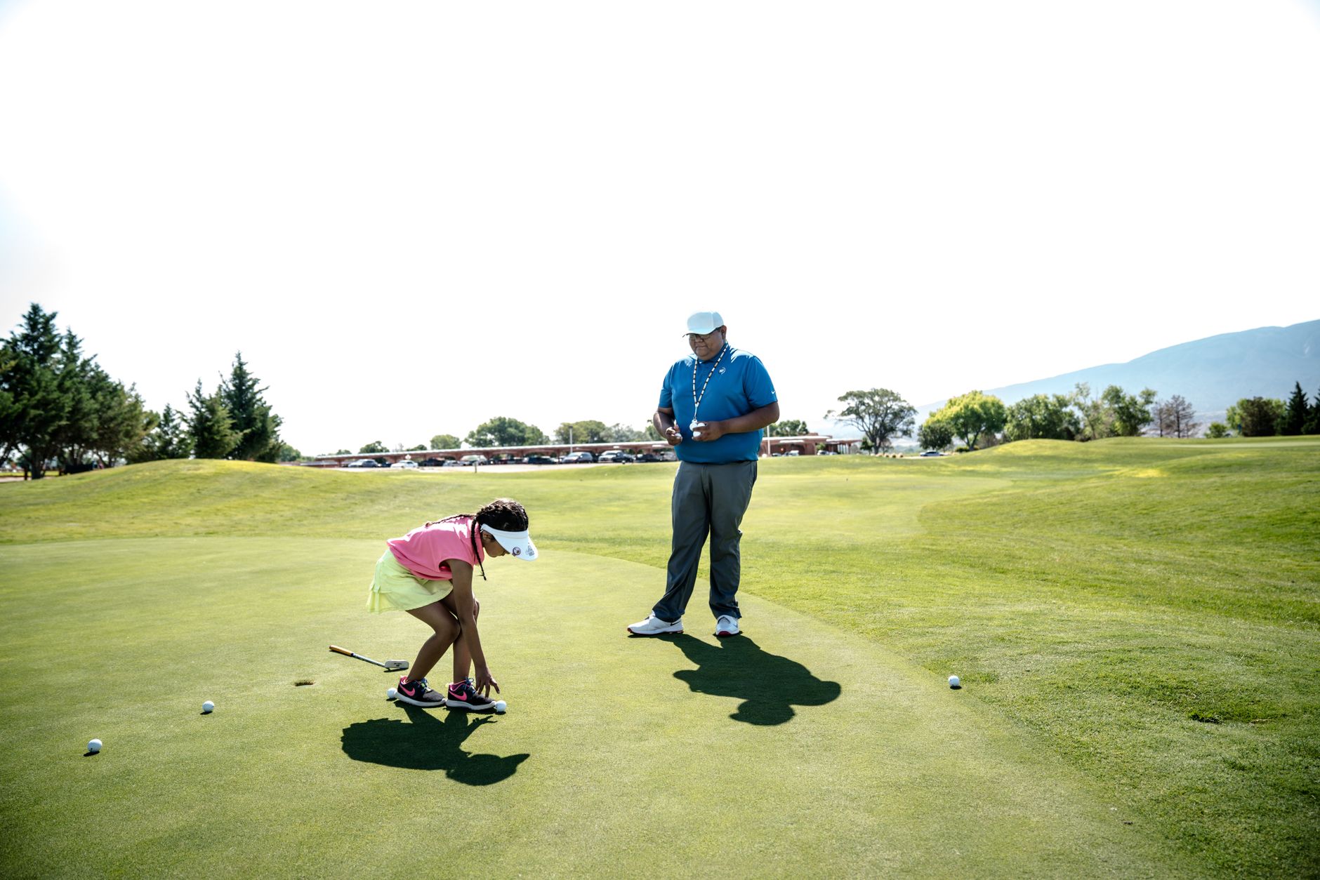 Moniteur de golf accompagnant une jeune golfeuse sur le green