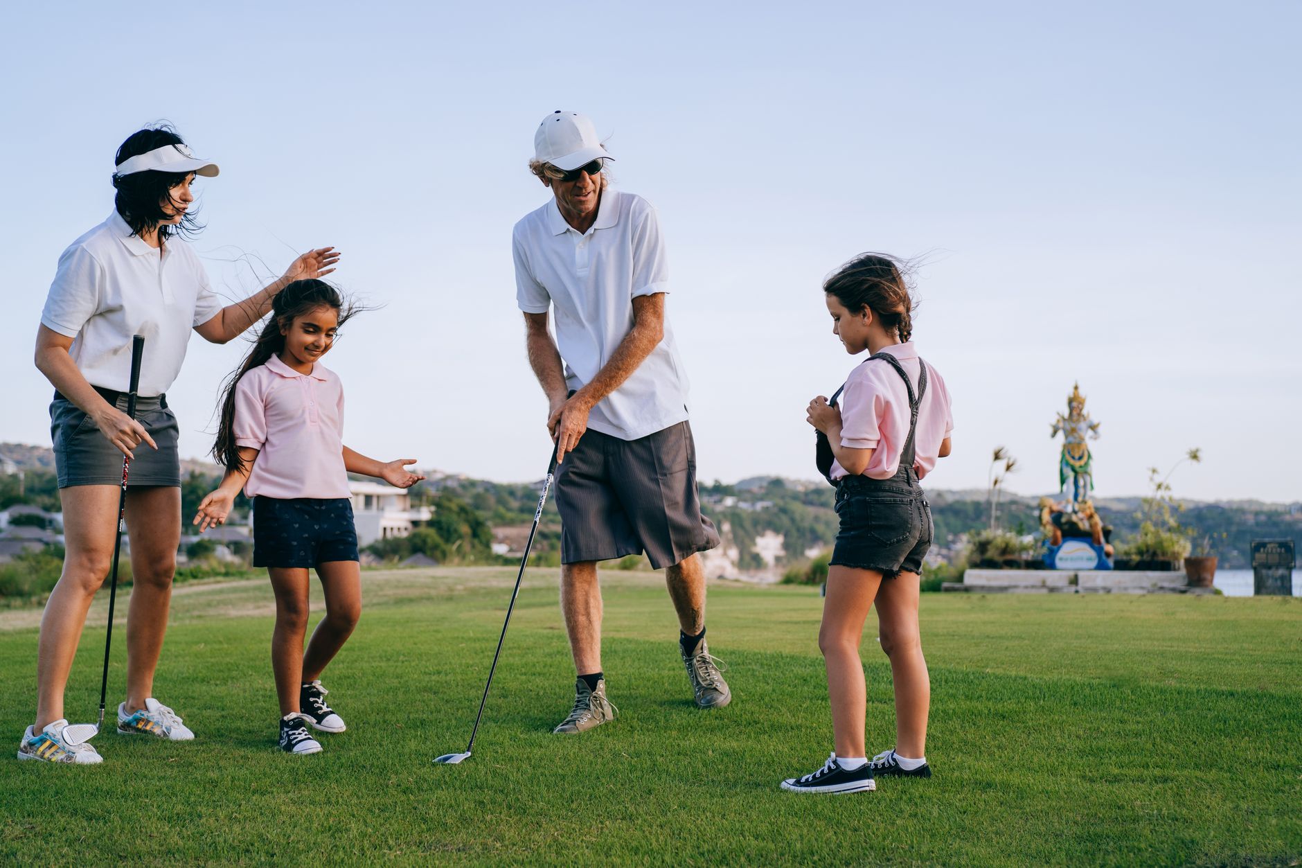 Famille avec deux jeunes filles s'initiant au golf en plein air